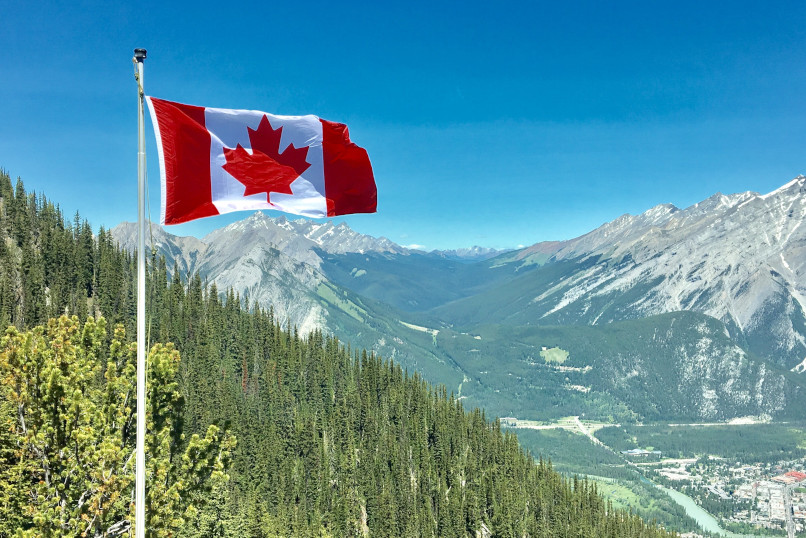 canada flag over mountains