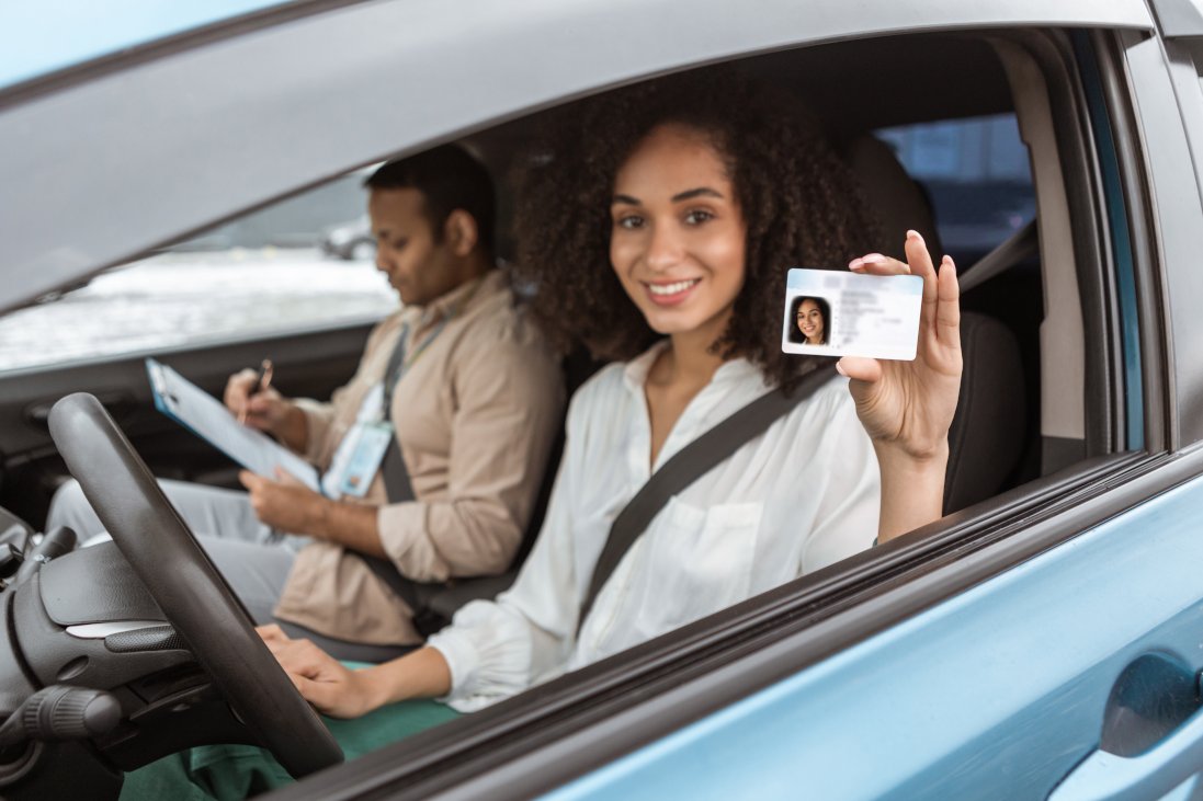 Cheerful Arabic beginner driving lesson driver Lady Showing Driving License Card Through Open Automobile Window, Sitting Beside Instructor Man In Car. Woman Got Her Driver's Permit